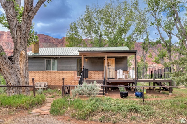 7020 E Creekside Ln, Castle Valley, UT 84532 - view of front facade with a chimney, metal roof, covered porch, and a mountain view