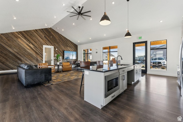 8518 W Cordero Dr, Magna, UT 84044 - kitchen with a sink, wood walls, stainless steel microwave, open floor plan, and white cabinets