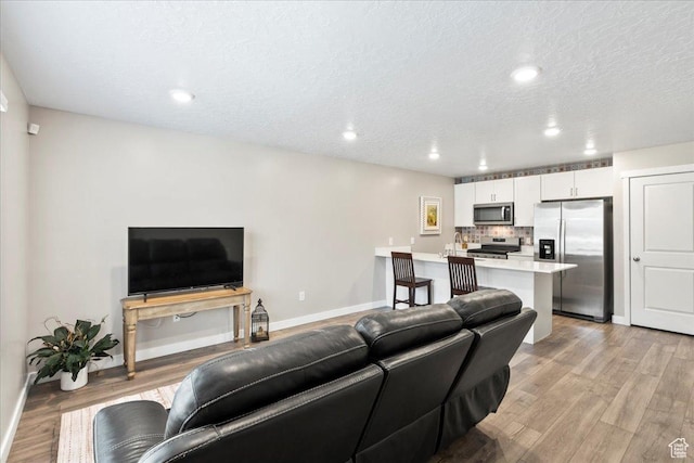 8518 W Cordero Dr, Magna, UT 84044 - living room featuring light wood-style floors, baseboards, recessed lighting, and a textured ceiling