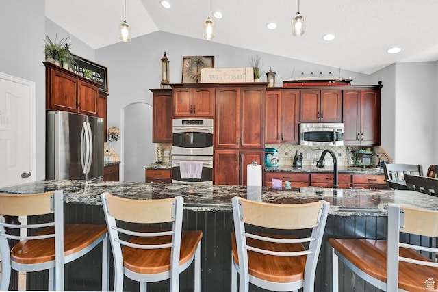 7776 S 2175 E, South Weber, UT 84405 - kitchen featuring appliances with stainless steel finishes, vaulted ceiling, tasteful backsplash, decorative light fixtures, and reddish brown cabinets