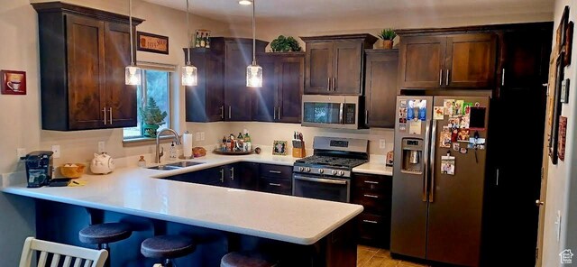 1158 E Ashdown Rd, Cedar City, UT 84721 - kitchen featuring appliances with stainless steel finishes, a sink, dark brown cabinetry, light countertops, and a peninsula