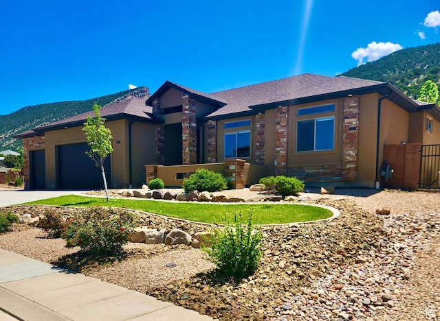 1158 E Ashdown Rd, Cedar City, UT 84721 - prairie-style house featuring a mountain view, a garage, driveway, stone siding, and a shingled roof