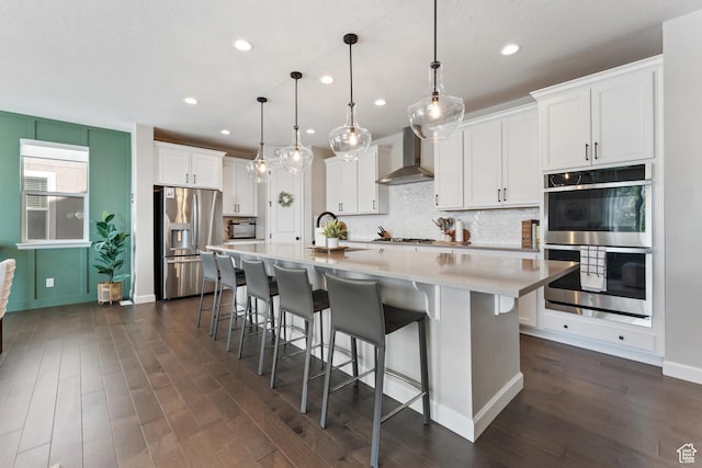 963 W Minuteman Ln, Saratoga Springs, UT 84045 - kitchen featuring stainless steel appliances, wall chimney range hood, dark wood-type flooring, backsplash, and white cabinetry
