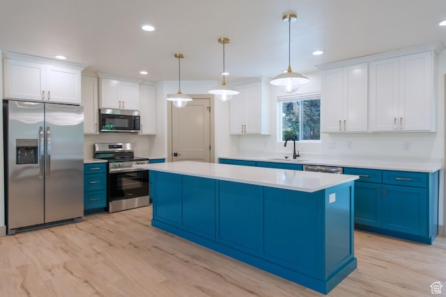 286 E 870 N, Logan, UT 84321 - kitchen featuring appliances with stainless steel finishes, blue cabinetry, a sink, a kitchen island, and light countertops
