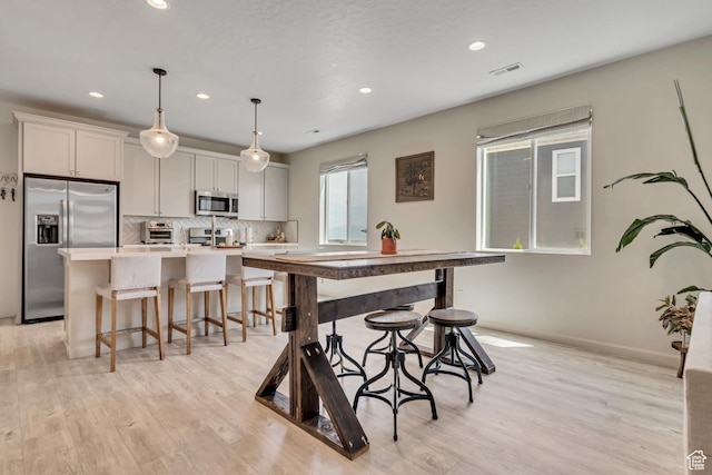 2103 N Elderberry Dr W Unit 222, Saratoga Springs, UT 84045 - kitchen with appliances with stainless steel finishes, a kitchen island with sink, a breakfast bar, backsplash, and recessed lighting