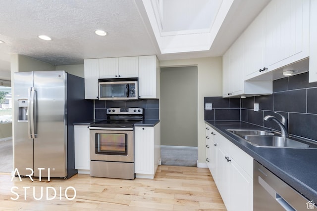 162 E 3000 S, Bountiful, UT 84010 - kitchen with appliances with stainless steel finishes, a sink, light wood-style floors, dark countertops, and a textured ceiling