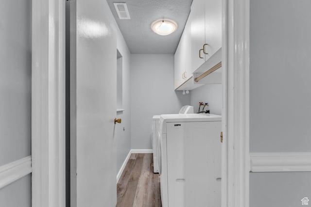 648 E 6870 S, Midvale, UT 84047 - laundry area with wood finished floors, washing machine and dryer, cabinet space, a textured ceiling, and baseboards