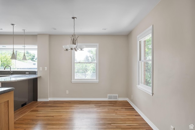 2366 E Logan Way, Salt Lake City, UT 84108 - unfurnished dining area with light wood-style flooring, plenty of natural light, a sink, and a chandelier