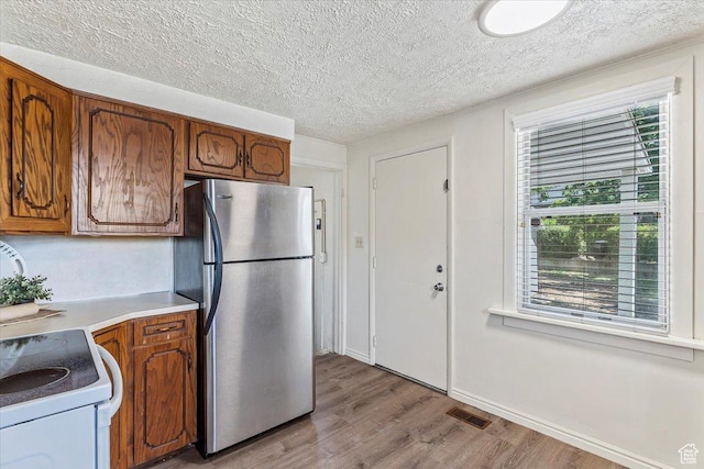 106 N 400 E, Kaysville, UT 84037 - kitchen featuring freestanding refrigerator, light wood-style floors, brown cabinets, a textured ceiling, and light countertops