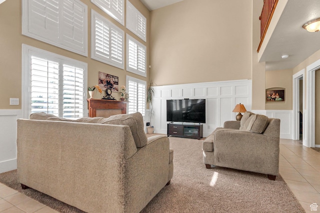 2733 S 1415 W, Syracuse, UT 84075 - living area with light tile patterned floors, a high ceiling, a decorative wall, a fireplace, and wainscoting