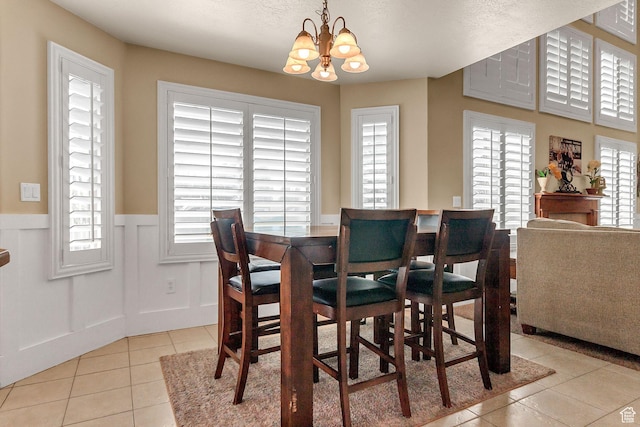 2733 S 1415 W, Syracuse, UT 84075 - dining space featuring light tile patterned floors, plenty of natural light, a chandelier, wainscoting, and a decorative wall