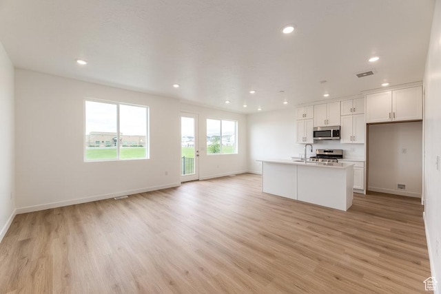 6064 W Lower Ln Unit 8-222, West Jordan, UT 84081 - kitchen featuring stainless steel microwave, light wood-style flooring, open floor plan, baseboards, and recessed lighting