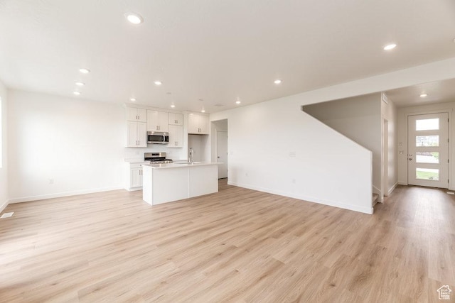 6064 W Lower Ln Unit 8-222, West Jordan, UT 84081 - unfurnished living room featuring baseboards, light wood-style floors, recessed lighting, and a sink