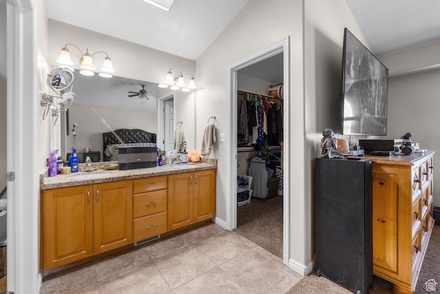 7819 S Spruce Tree Ln, Sandy, UT 84094 - bathroom featuring a ceiling fan, vaulted ceiling, tile patterned flooring, vanity, and a walk in closet