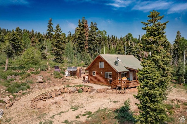 706 W Tranquility Dr, Virgin, UT 84779 - view of side of home with an exterior structure, a wooden deck, an outdoor structure, log exterior, and a view of trees