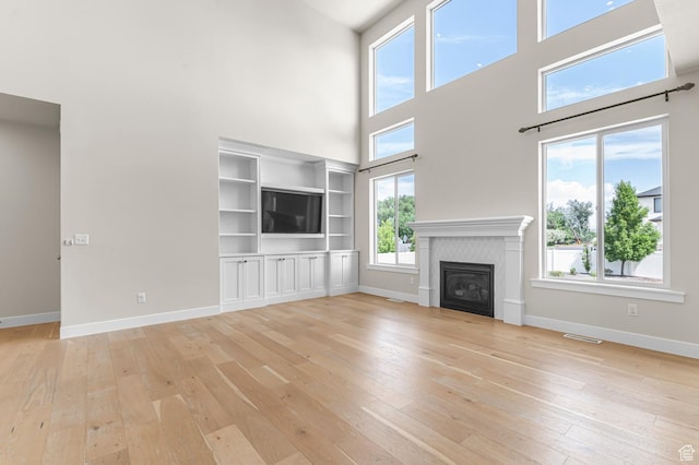1676 W Timp Meadows Dr, Lehi, UT 84043 - unfurnished living room featuring a towering ceiling, light wood finished floors, baseboards, and a glass covered fireplace