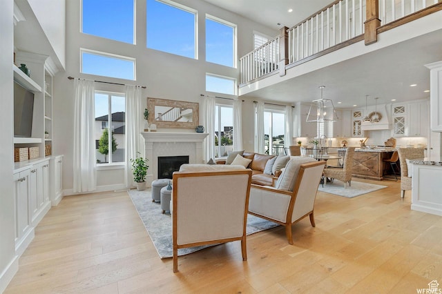 1676 W Timp Meadows Dr, Lehi, UT 84043 - living room with light wood-style flooring, a towering ceiling, a glass covered fireplace, and recessed lighting