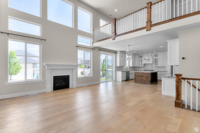 1676 W Timp Meadows Dr, Lehi, UT 84043 - unfurnished living room featuring a fireplace, light wood-style flooring, a high ceiling, a sink, and recessed lighting