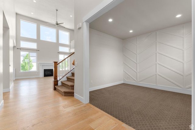 1676 W Timp Meadows Dr, Lehi, UT 84043 - spare room with ceiling fan, stairs, a glass covered fireplace, recessed lighting, and light wood finished floors