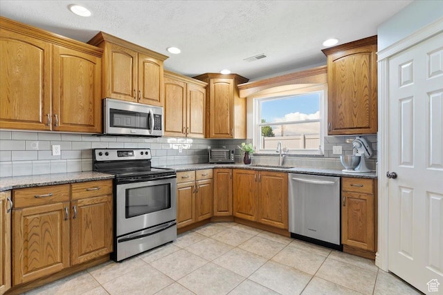 286 W 1875 N, North Ogden, UT 84414 - kitchen featuring appliances with stainless steel finishes, a sink, backsplash, light tile patterned flooring, and stone counters