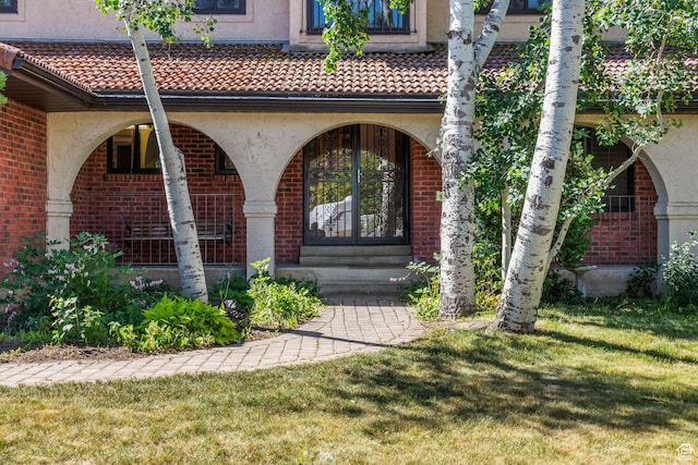1922 E Southbridge Way, Sandy, UT 84093 - view of exterior entry with brick siding, a lawn, a tiled roof, and a porch