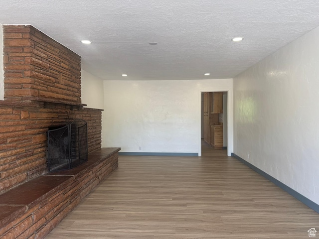 559 E Harmston Ave, Roosevelt, UT 84066 - unfurnished living room featuring wood finished floors, a fireplace, baseboards, recessed lighting, and a textured ceiling