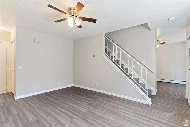 190 W 1100 N, Logan, UT 84341 - unfurnished living room with a baseboard heating unit, ceiling fan, wood finished floors, stairway, and baseboards