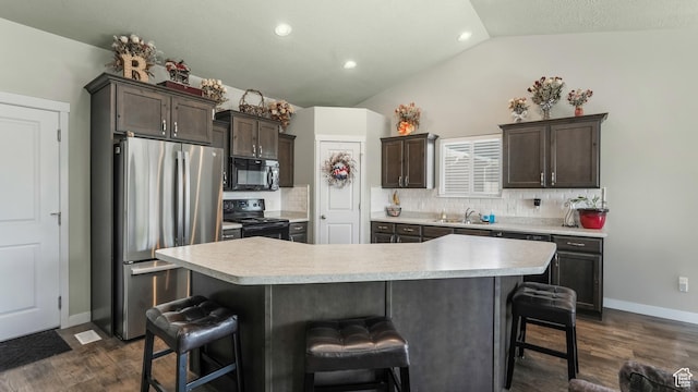 1026 E Searle Ln, Eagle Mountain, UT 84005 - kitchen with black appliances, lofted ceiling, light countertops, a kitchen bar, and decorative backsplash