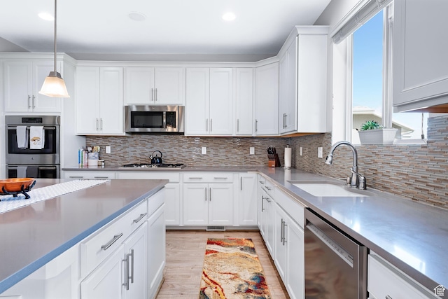 227 E Sandhill Dr, Saratoga Springs, UT 84045 - kitchen with appliances with stainless steel finishes, a sink, white cabinetry, light wood-style floors, and hanging light fixtures