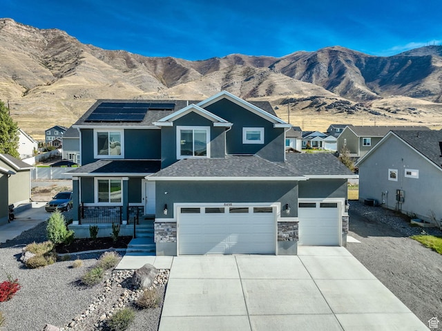 8498 N Colette St, Lake Point, UT 84074 - view of front of property featuring stone siding, stucco siding, concrete driveway, solar panels, and a mountain view