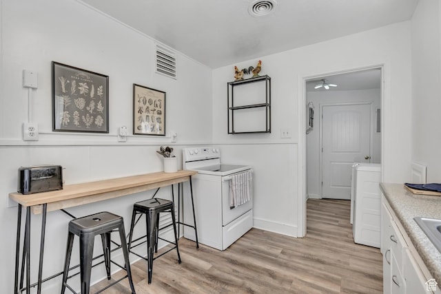 232 E 5900 S, Murray, UT 84107 - kitchen featuring white electric range, light wood-style floors, white cabinets, a breakfast bar area, and a sink