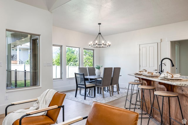 5865 Belmont Dr, Mountain Green, UT 84050 - dining area featuring a chandelier, light wood-style floors, baseboards, and a textured ceiling