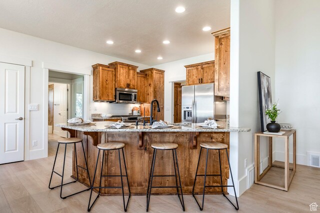 5865 Belmont Dr, Mountain Green, UT 84050 - kitchen with appliances with stainless steel finishes, light wood-style flooring, recessed lighting, a peninsula, and light stone counters