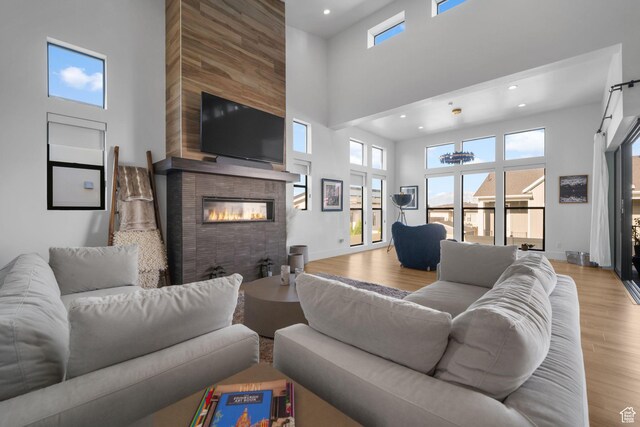 12277 S Emory Peak Cv Unit 404, Herriman, UT 84096 - living area with a high ceiling, a fireplace, wood finished floors, recessed lighting, and baseboards
