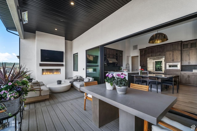 12277 S Emory Peak Cv Unit 404, Herriman, UT 84096 - wooden terrace with outdoor dining area, a sink, and an outdoor living space with a fireplace