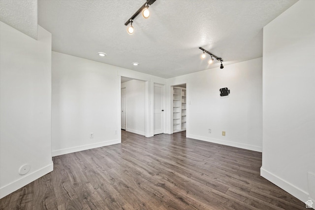 2951 N 1200 E, North Logan, UT 84341 - empty room featuring rail lighting, a textured ceiling, baseboards, dark wood finished floors, and built in features