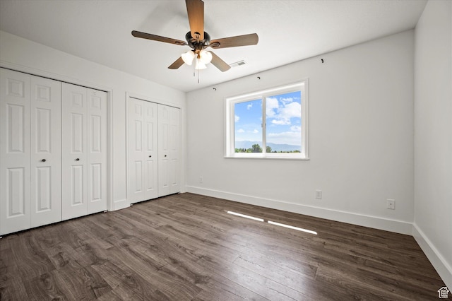 2951 N 1200 E, North Logan, UT 84341 - unfurnished bedroom featuring multiple closets, baseboards, wood finished floors, and a ceiling fan