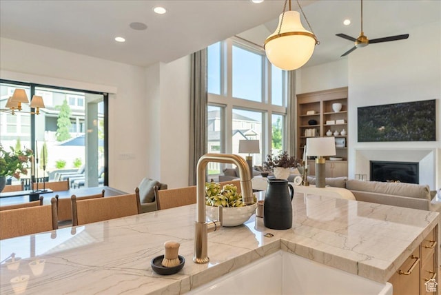 812 N 780 W, American Fork, UT 84003 - kitchen with open floor plan, a glass covered fireplace, a sink, recessed lighting, and hanging light fixtures