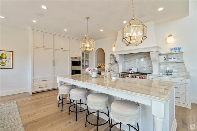 807 N 780 W, American Fork, UT 84003 - kitchen with light wood-style floors, a chandelier, decorative backsplash, arched walkways, and stainless steel double oven