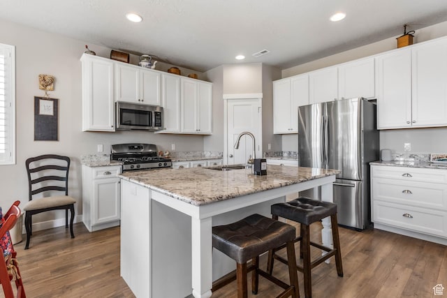 1165 W Silver Hollow Rd, Syracuse, UT 84075 - kitchen with stainless steel appliances, a sink, dark wood finished floors, a breakfast bar area, and white cabinetry