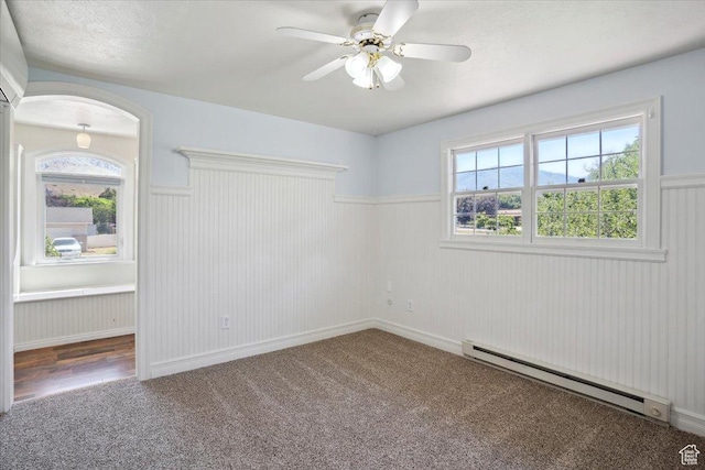 263 W 800 N, Brigham City, UT 84302 - carpeted empty room featuring a baseboard heating unit, a wainscoted wall, a ceiling fan, healthy amount of natural light, and arched walkways