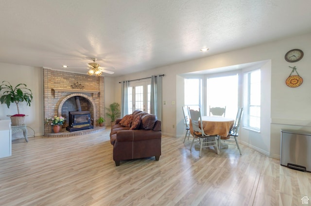 5760 S 1050 E, South Ogden, UT 84405 - living area with a wood stove, light wood-style floors, a textured ceiling, ceiling fan, and baseboards