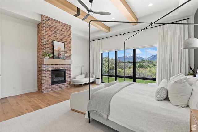11527 S River Front Pkwy W, South Jordan, UT 84095 - bedroom featuring beam ceiling, wood finished floors, a brick fireplace, baseboards, and a mountain view