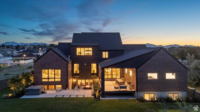 11527 S River Front Pkwy W, South Jordan, UT 84095 - back of house at dusk featuring a patio, a lawn, and brick siding