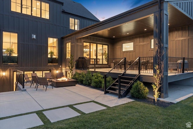 11527 S River Front Pkwy W, South Jordan, UT 84095 - back of house at dusk with board and batten siding, an outdoor fire pit, a patio area, a lawn, and stairs