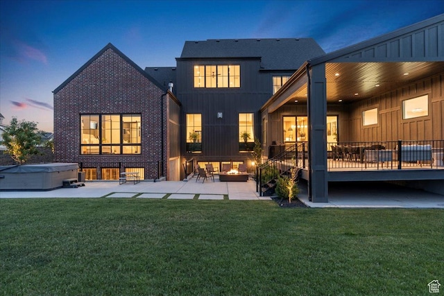 11527 S River Front Pkwy W, South Jordan, UT 84095 - back of house at dusk with a hot tub, a patio, a lawn, and brick siding