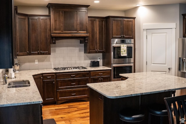 66 N 325th St E, Farmington, UT 84025 - kitchen featuring stainless steel appliances, dark brown cabinetry, a kitchen breakfast bar, backsplash, and a sink