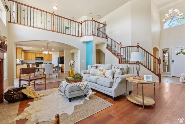 2271 W Pointe Meadow Dr N, Lehi, UT 84043 - living room with a towering ceiling, a chandelier, arched walkways, stairs, and light wood-type flooring