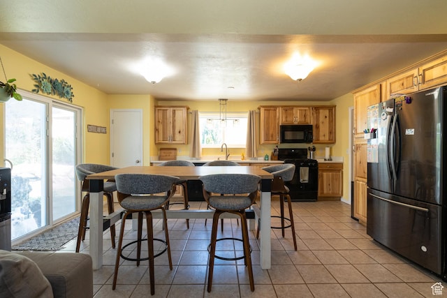 1250 N Lewis Peak Dr, Ogden, UT 84404 - kitchen featuring black appliances, light tile patterned floors, a sink, a kitchen breakfast bar, and a center island