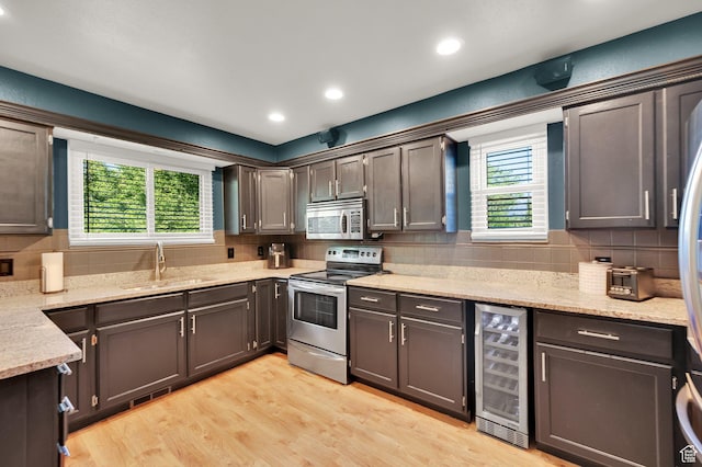 6767 S 1600 W, West Jordan, UT 84084 - kitchen with beverage cooler, stainless steel appliances, a sink, tasteful backsplash, and light wood finished floors